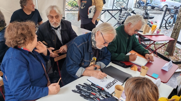 Florence Cestac en discussion avec Jean-Michel Nicollet, tandis que Frank Margerin et Jacques de Loustal dessinent aux Journées BD de Clichy 2025, sous le regard de Daniel Gauckle