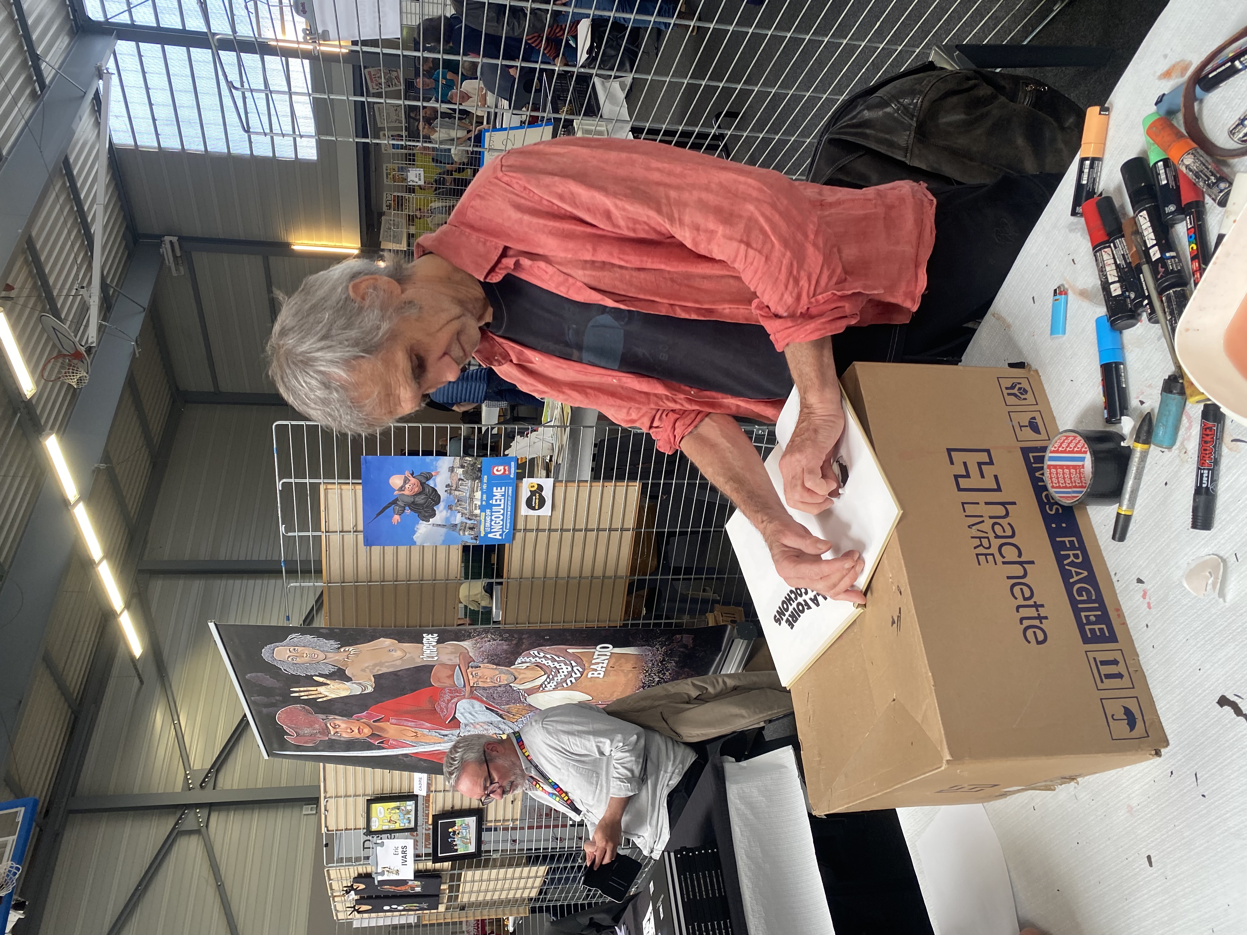 Le dessinateur Ptiluc déchirant la page d'un album BD pour une dédicace