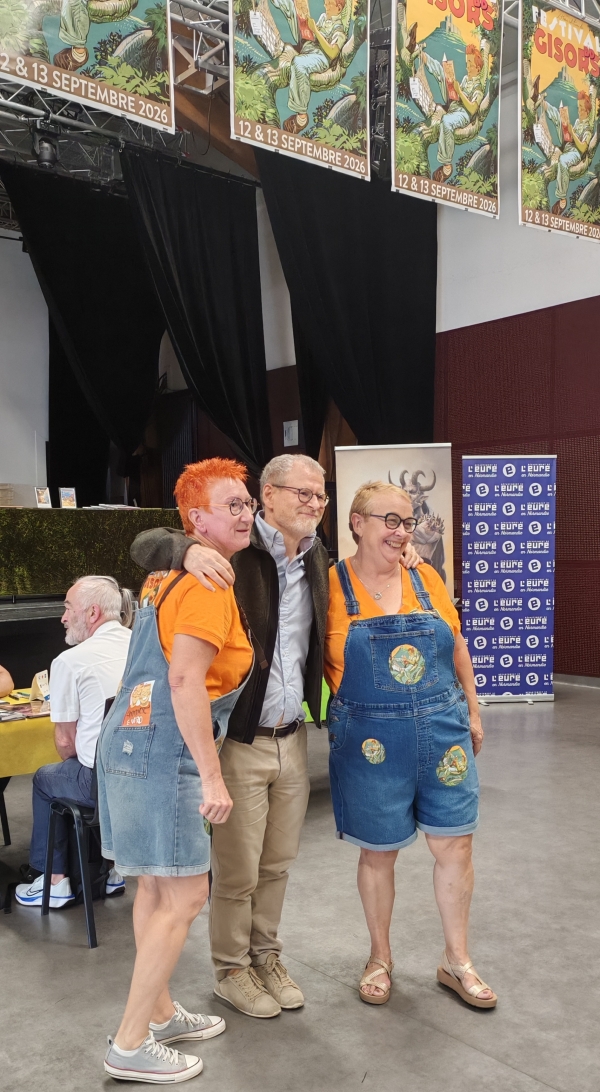 Annick Véro Gisors Hirn Les organisatrices Annick et Véro entourant Laurent Hirn, dessinateur du Pouvoir des Innocents et de l'affiche du festival